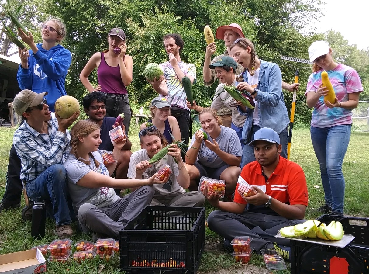 Students holding produce in a garden